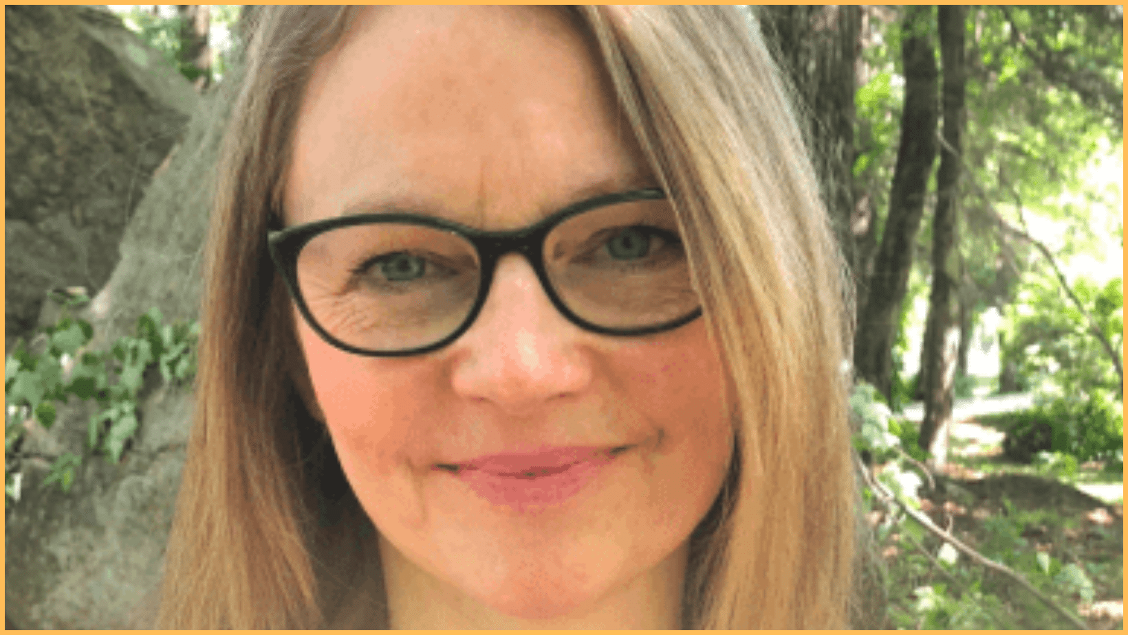 Person with glasses smiling outdoors