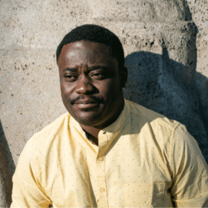 Man in yellow shirt against stone wall