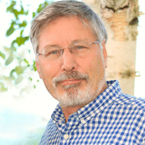Man with glasses standing outdoors smiling