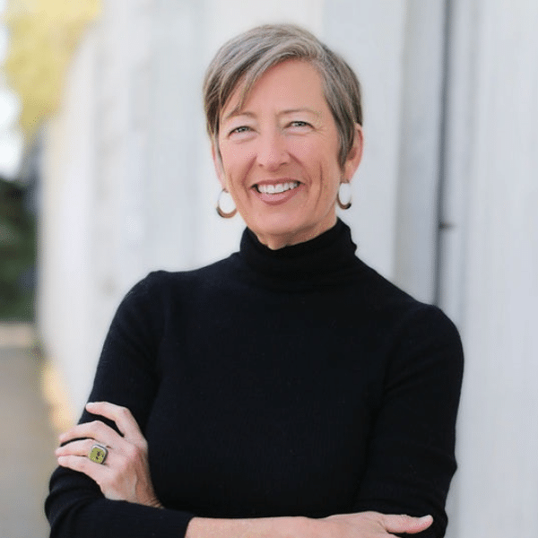 Smiling person in black sweater outdoors.