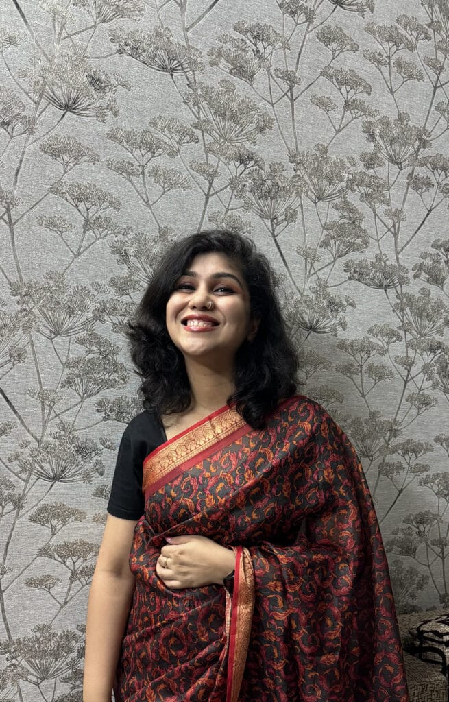 Smiling woman in red patterned sari, floral wallpaper