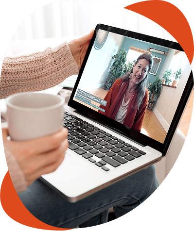 Person holding coffee, video call on laptop screen.
