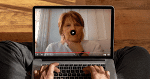 Person watching video conference on laptop.