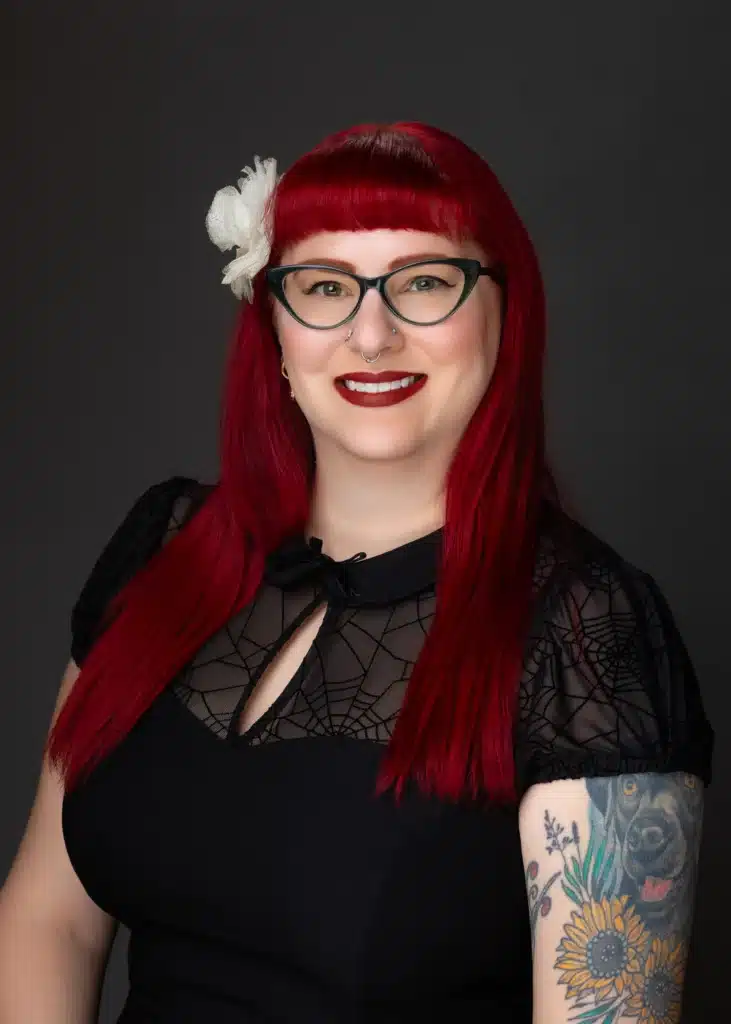 Smiling woman with red hair and tattoos.