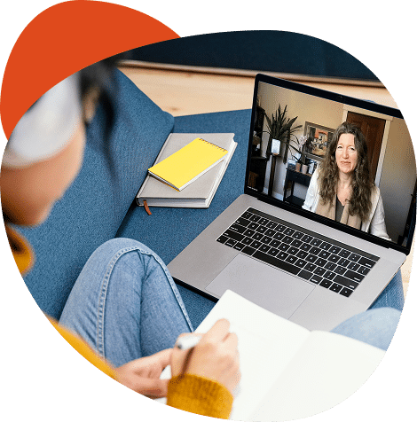 Woman video conferencing on laptop, taking notes