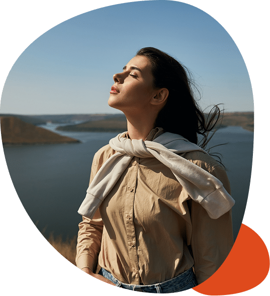 Woman enjoys fresh air by the lake.