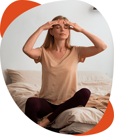 Woman meditating in bedroom on bed.