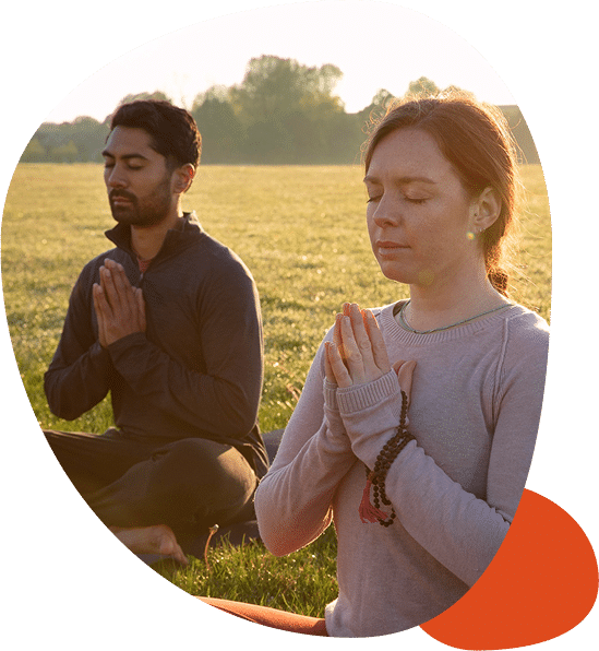 Two people meditating in a sunny field