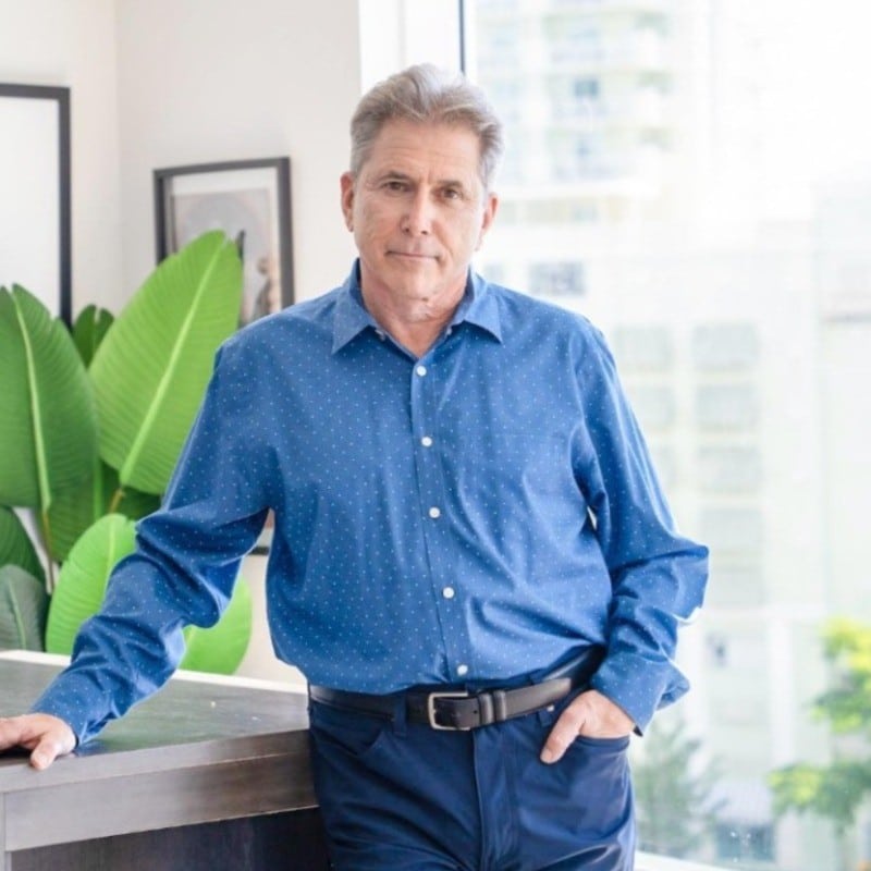 Man in blue shirt standing indoors.