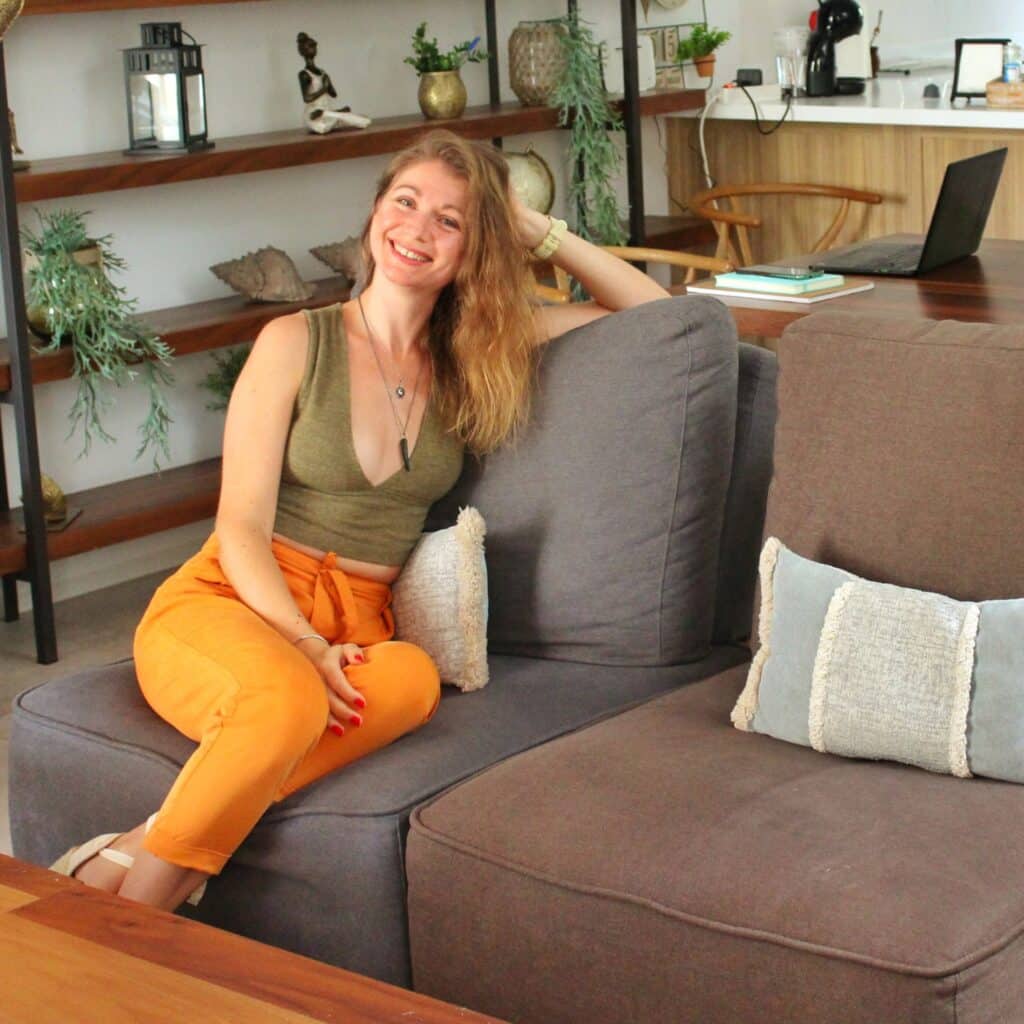 Woman smiling on gray couch in cozy living room.