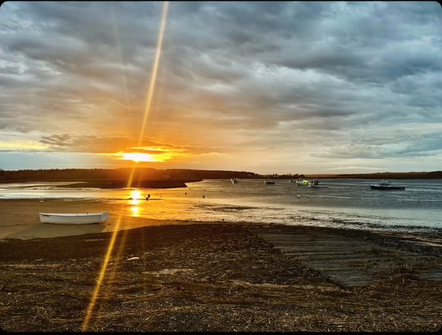 Sunset over boats in a tranquil harbor scene.