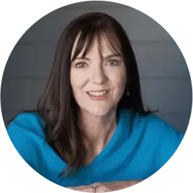 Smiling person in blue shirt, gray background.