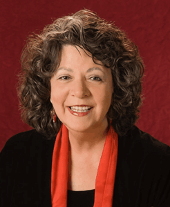 Smiling person with curly hair and red scarf.