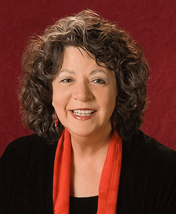 Smiling person with curly hair and red scarf.