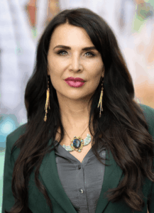 Woman with long dark hair, wearing a green jacket.