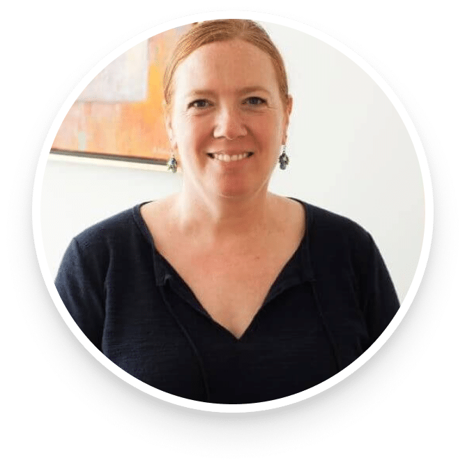 Smiling woman with red hair and earrings indoors.