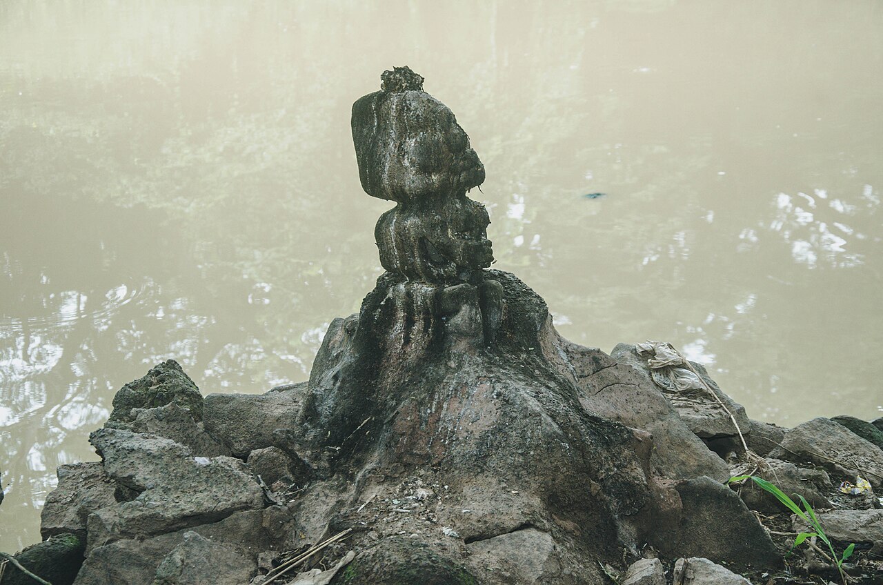 Stone statue on rocks near water