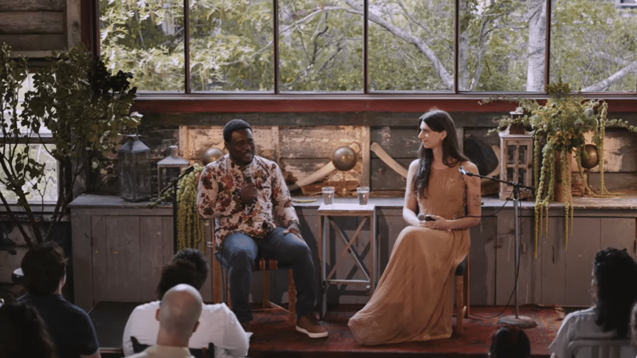 Two people speaking at a casual indoor event.