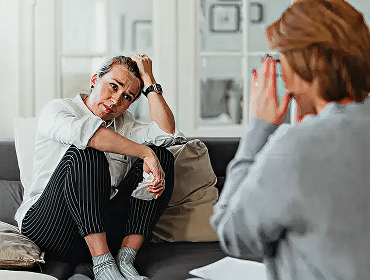 Therapy session with two women conversing on couch.