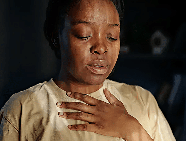 Person holding chest, appearing emotional or reflective.