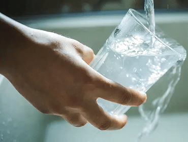 Hand holding glass under running water