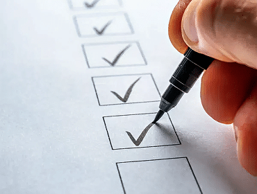 Person checking boxes on a checklist with pen.