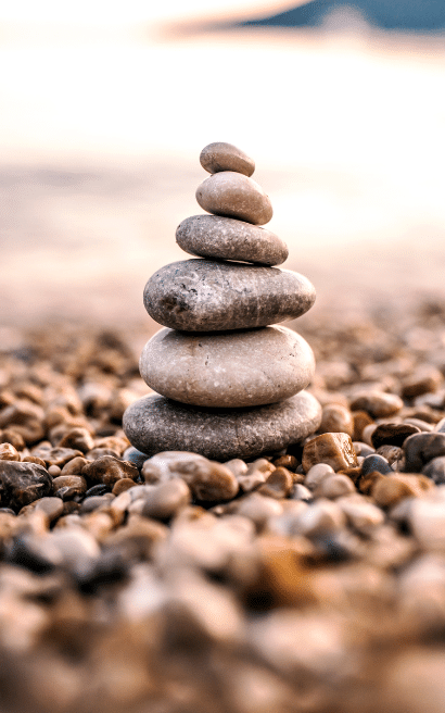Stacked pebbles on beach at sunset