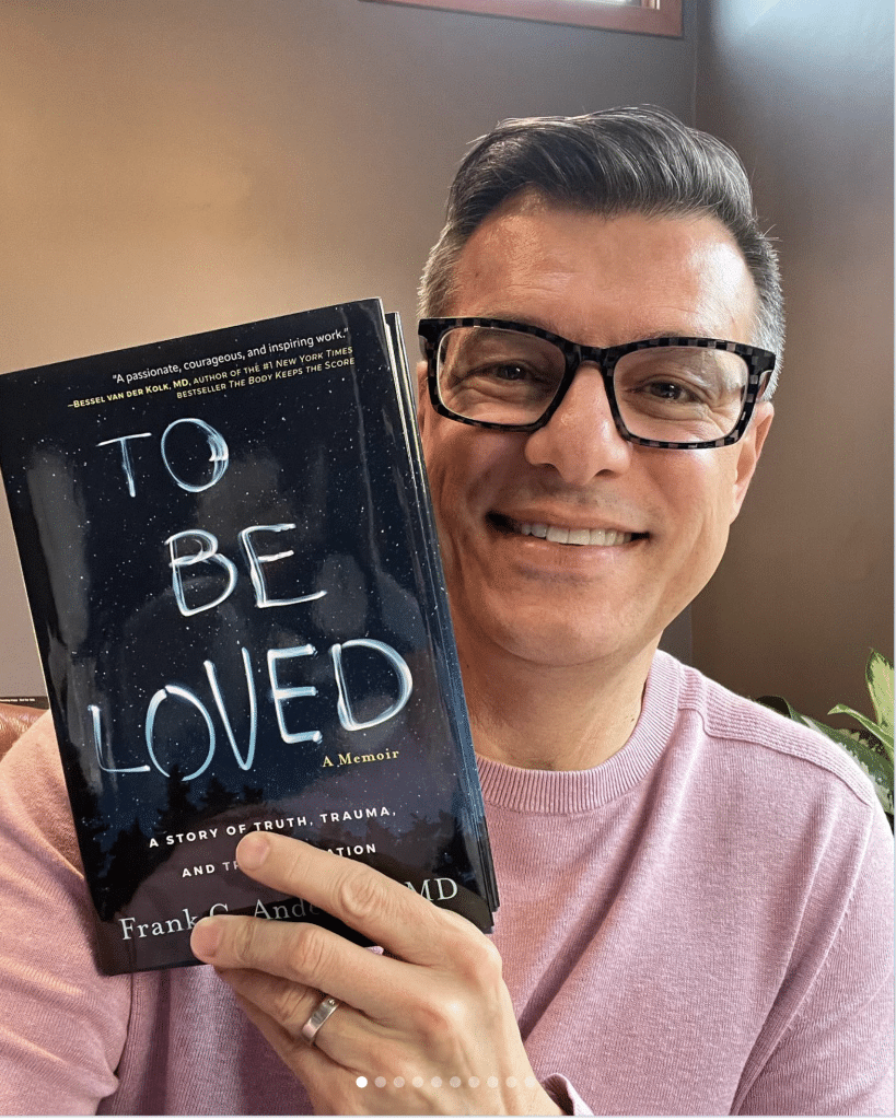 Man holding "To Be Loved" memoir book