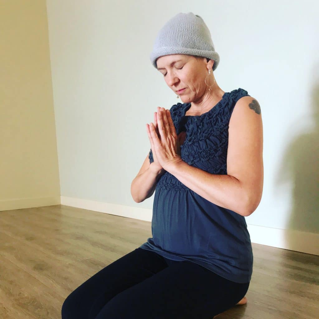 Person kneeling with hands in prayer pose indoors
