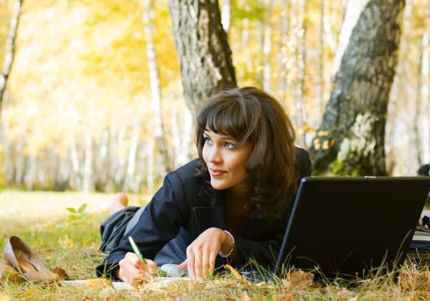 Young businesswoman using laptop in the birch forest.