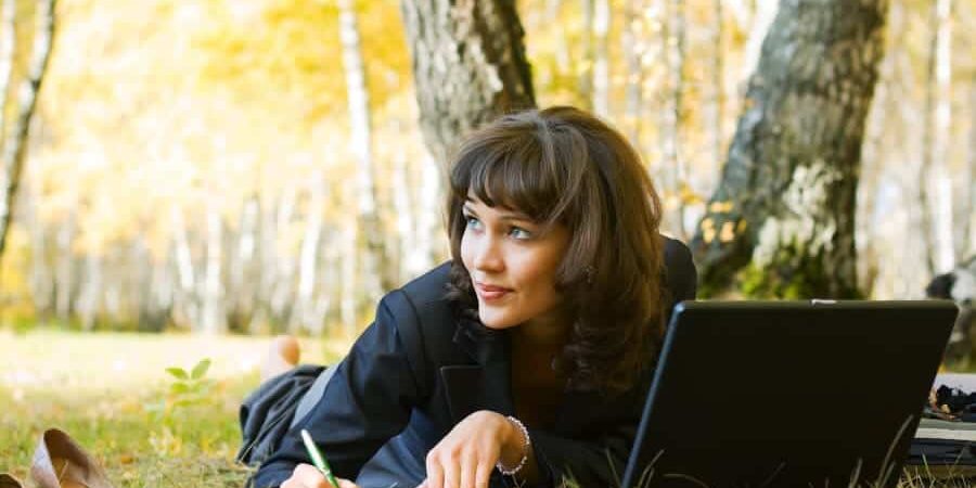 Young businesswoman using laptop in the birch forest.